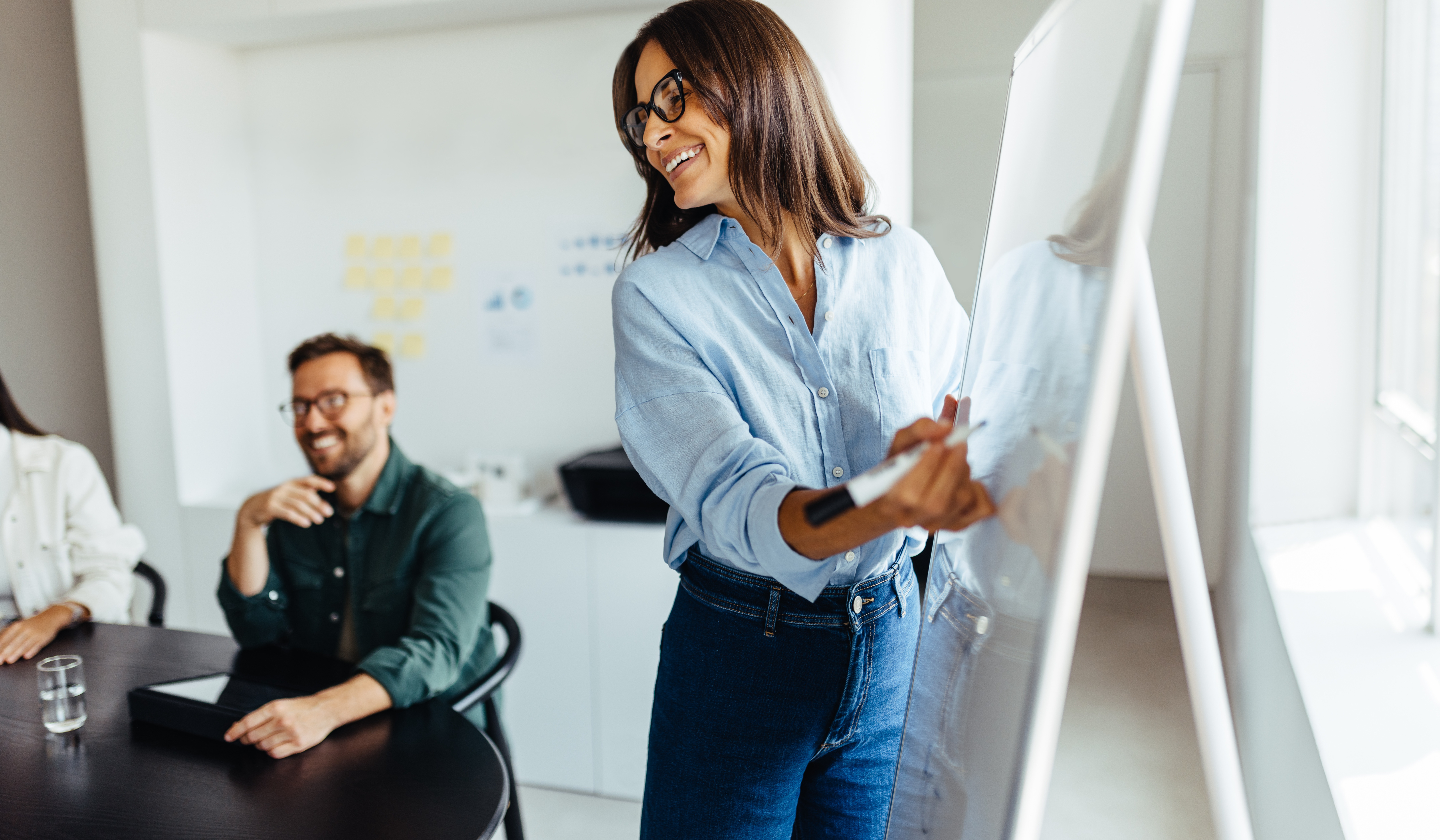 B2B marketing professionals collaborating on AI-driven sales strategy during office presentation, demonstrating strategic planning for revenue growth and digital transformation initiatives