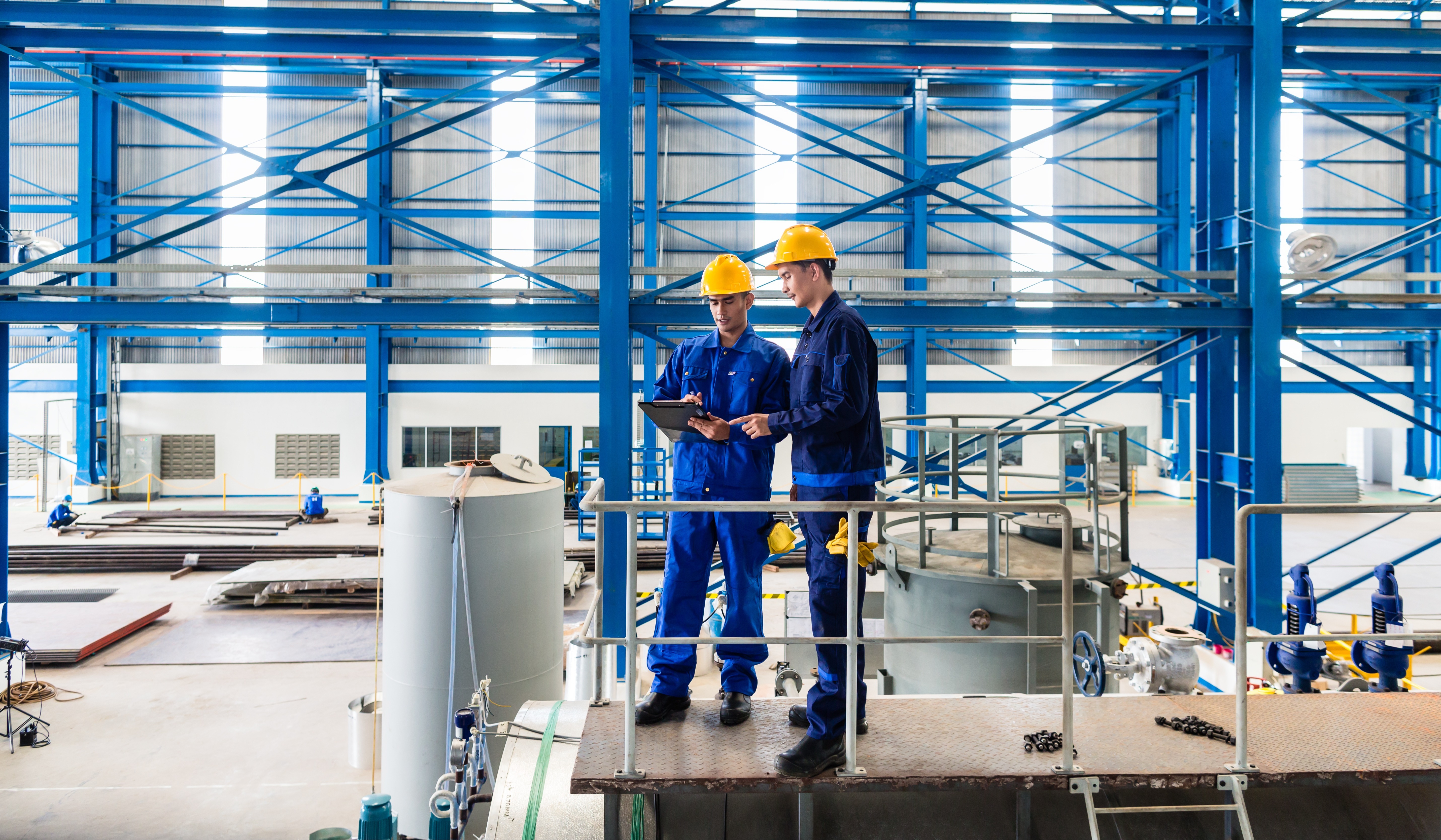 Manufacturing workers reviewing operational data on tablet in warehouse demonstrating legacy ERP system management